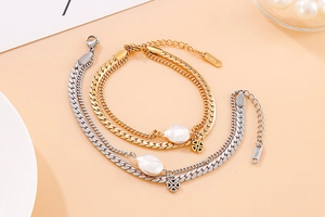 Detail of double-layer gold stainless steel bracelet with shell and clover charms