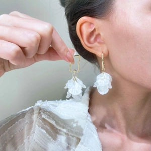 Boucles d'oreilles pétales en acrylique avec crochets dorés portées par un mannequin