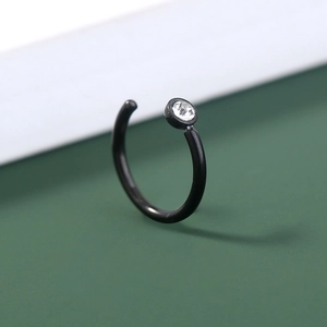 Macro shot of black stainless steel U-shaped nose ring with a clear round zircon stone