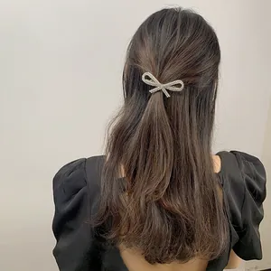 Sparkling rhinestone bow hair clip shown on model's dark brown wavy long hair