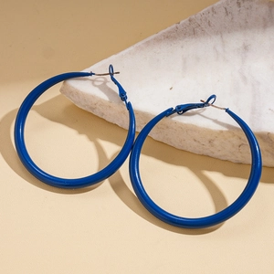 Detailed close-up of large blue enamel geometric hoop earrings on a marble base
