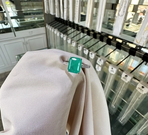 Macro view of emerald green rectangular gemstone and white cubic zirconia accents