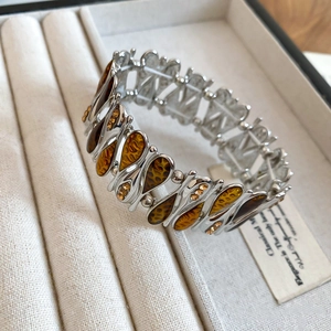 Macro shot of silver-tone elastic bracelet with amber teardrop patterns and crystals