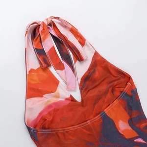 Detailed close-up of the deep V-neckline and abstract orange print on this halter dress