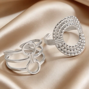 Detailed shot of silver geometric rings with tiered bands and studded disc on silk