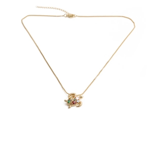 Close-up of golden turtle necklace featuring colorful inlaid crystals and lobster clasp