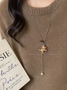 Detail of a vintage rocking horse pendant necklace with pearl on a brown knit sweater