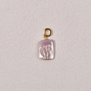 Macro view of a purple baroque pearl with golden clasp showing iridescent luster