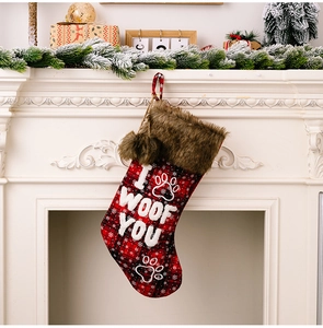 Detail of red plaid Christmas stocking with 'I WOOF YOU' embroidery on a cozy fireplace
