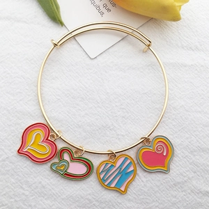 Golden alloy bracelet with four colorful heart enamel charms on a white texture background