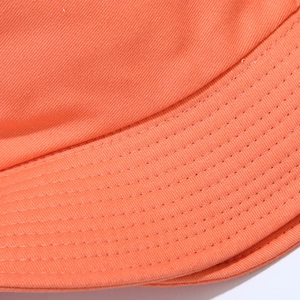 Detailed close-up of orange cotton bucket hat brim featuring durable multi-row stitching