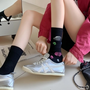 Detail of black combed cotton socks with colorful abstract patterns and silver sneakers