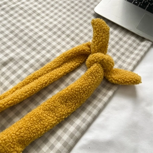 Gros plan d'une sangle en peluche jaune gingembre avec un nœud et une texture douce
