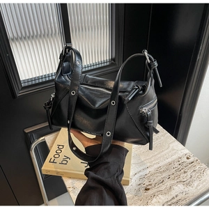 Close-up of black leather biker tote bag featuring silver hardware and eyelet strap detail