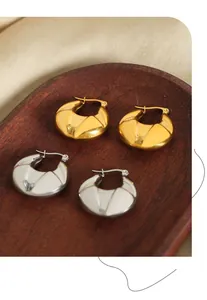 Gros plan de boucles d'oreilles en U en forme de larme dorées et argentées sur un plateau
