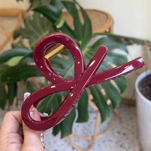Detail of burgundy large bow hair claw clip featuring sleek glossy finish and metal spring