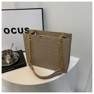 Detail of khaki tote bag featuring geometric quilted texture and gold chain strap