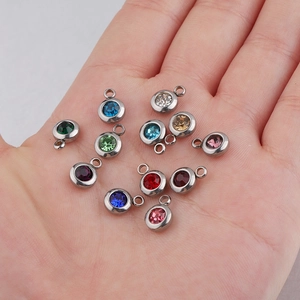 6.5mm stainless steel birthstone pendants in twelve colors displayed on a palm