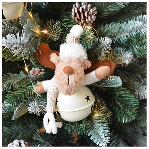 Plush reindeer Christmas bell ornament hanging on a pine tree branch with pinecones
