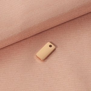 Detailed macro view of rose gold rectangular stainless steel pendant tag with top hole