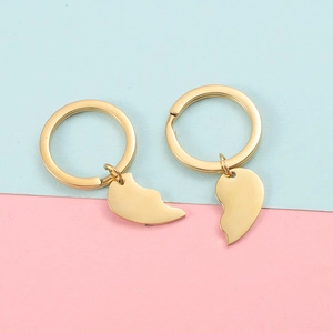 Close-up of polished gold split heart keychains for couples on a dual-color background