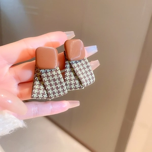 Detail view of vintage houndstooth fabric earrings with brown square resin studs