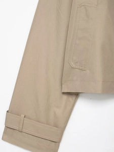 Detail of khaki trench coat featuring adjustable cuff straps and high-density twill fabric