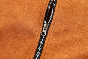 Macro shot of silver metal zipper on premium brown suede leather jacket texture