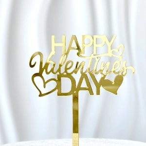 Close-up of gold acrylic Happy Valentine's Day cake topper with glossy heart details