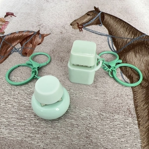 Macro view of mint green square and round fidget button keychains on patterned fabric