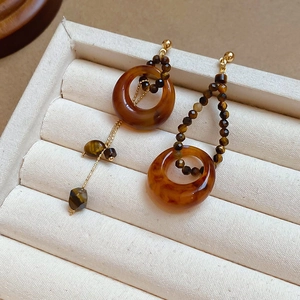 Détail de boucles d'oreilles asymétriques vintage avec perles brunes et pompon métal