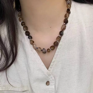 Detail of beaded necklace with irregular brown agate stones on a vintage choker