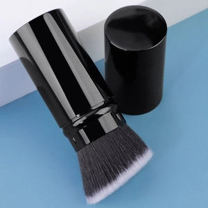 Macro shot of portable retractable makeup brush with synthetic bristles and black cap