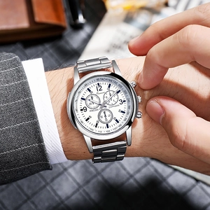 Close-up of a men's quartz watch with steel band and white dial on a suit sleeve