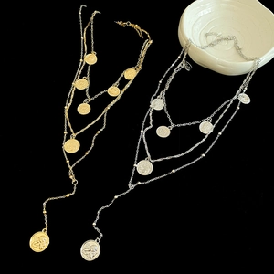 Macro shot of layered gold and silver portrait coin necklaces with vintage metallic texture