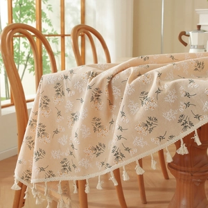 Detailed macro view of cotton linen tablecloth featuring vintage blue floral patterns and tassels