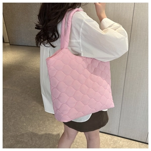 Pink quilted tote bag shown on model featuring puffer straps and wave pattern
