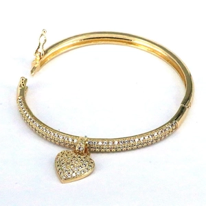 Close-up of golden heart bangle with micro-paved cubic zirconia and side hinge clasp