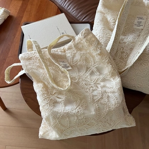 Beige lace embroidery cotton tote bag with French vintage style on a wooden table