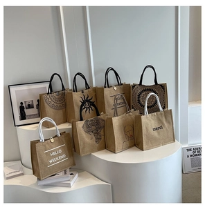 Detailed view of various printed jute tote bags on minimalist white stands