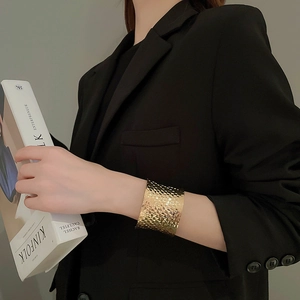 Detailed view of a wide woven texture gold cuff bracelet on a female model with sleek styling