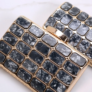 Detailed close-up of acrylic evening clutch with grey marble pattern and gold frame