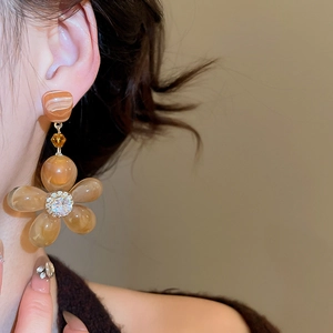 Close-up of amber resin flower earrings with sparkling zircon on an elegant model