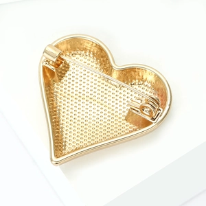 Detail of the golden heart brooch back showing pin fastener and textured metal finish