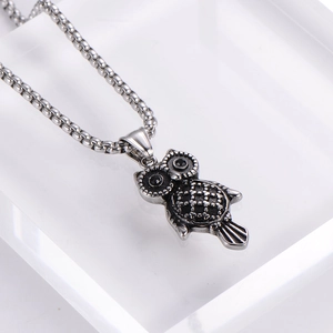 Macro shot of owl pendant featuring black crystal eyes and vintage stainless steel finish