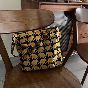 Détail du motif d'éléphant doré et de l'étiquette latérale sur un sac noir à l'épaule
