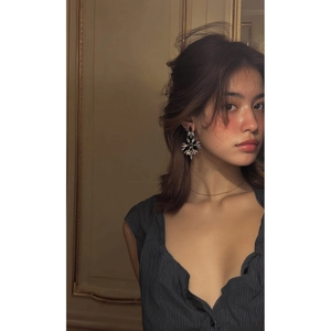 Détail de boucles d'oreilles pendantes étoilées avec cristaux portées par un mannequin en décor rétro