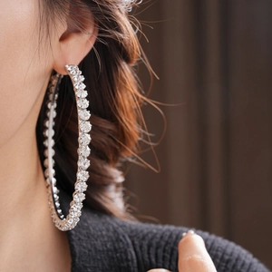 Detail view of large silver hoop earrings with shimmering rhinestones on a model