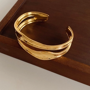 Detail showing irregular double-layered pleated gold bangle with textured wavy finish