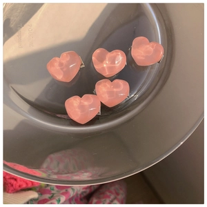 Close-up of five pink heart-shaped hair clips on a glass tray with warm sunset lighting
